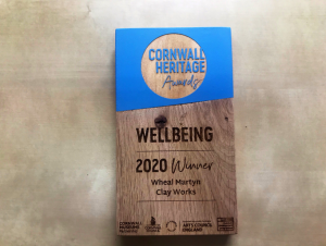 A wooden and blue awards plaque reads 'Cornwall Heritage Awards 2020; Wellbeing; Wheal Martyn Clay Works'